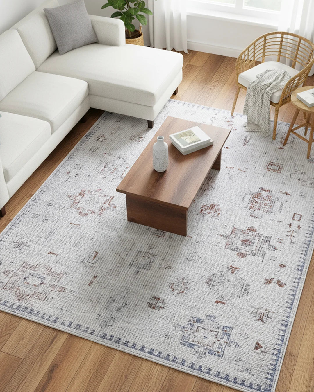 Living room with a patterned rug, white sofa, wooden coffee table, and wicker chair.