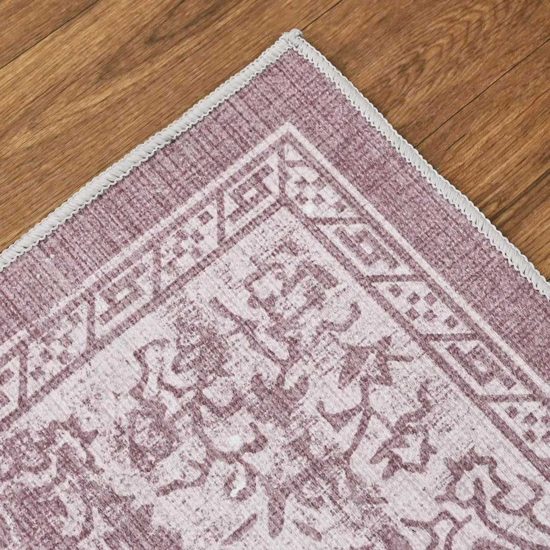 Close-up of a pink and white patterned rug on a wooden floor