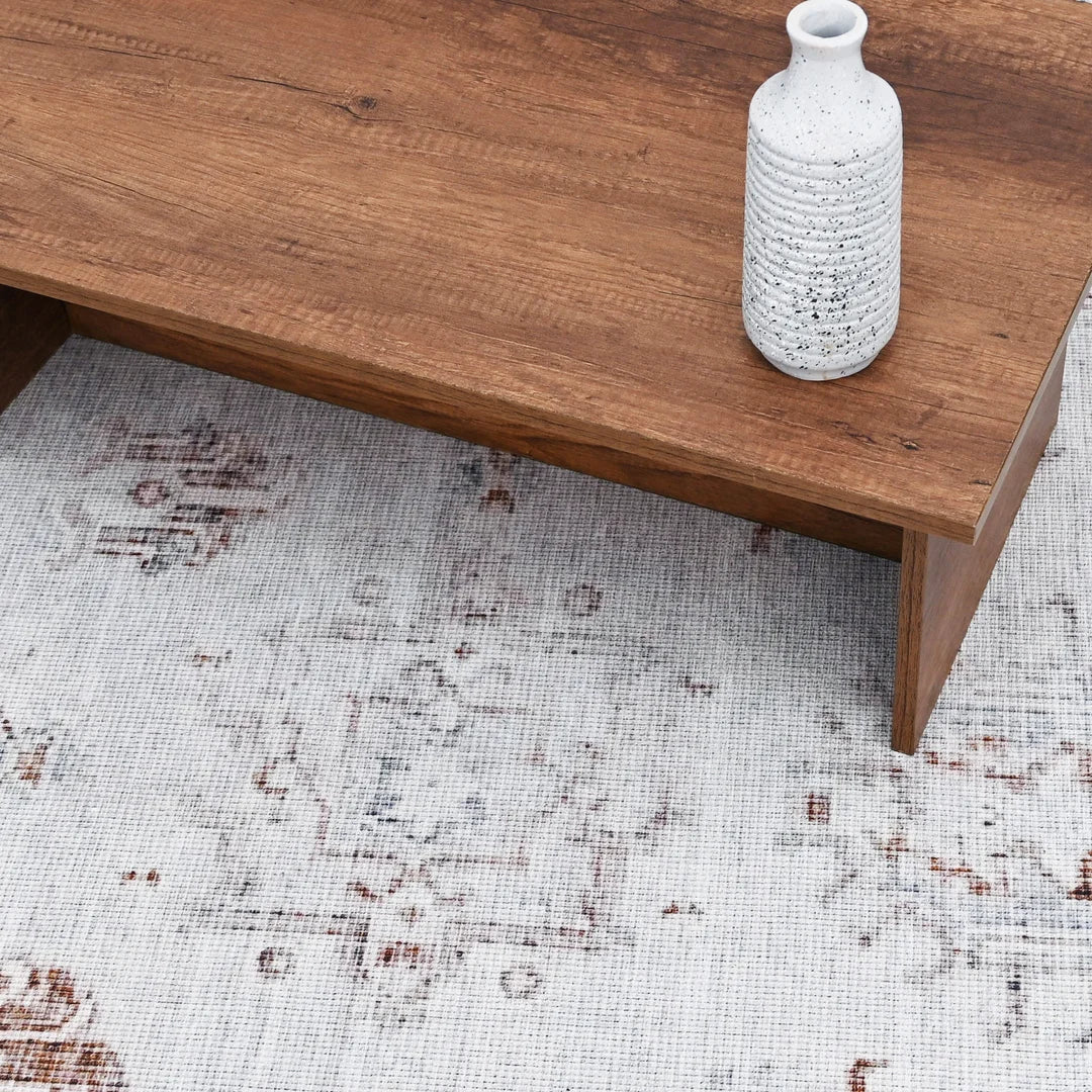 Wooden coffee table with a textured white vase on a patterned rug