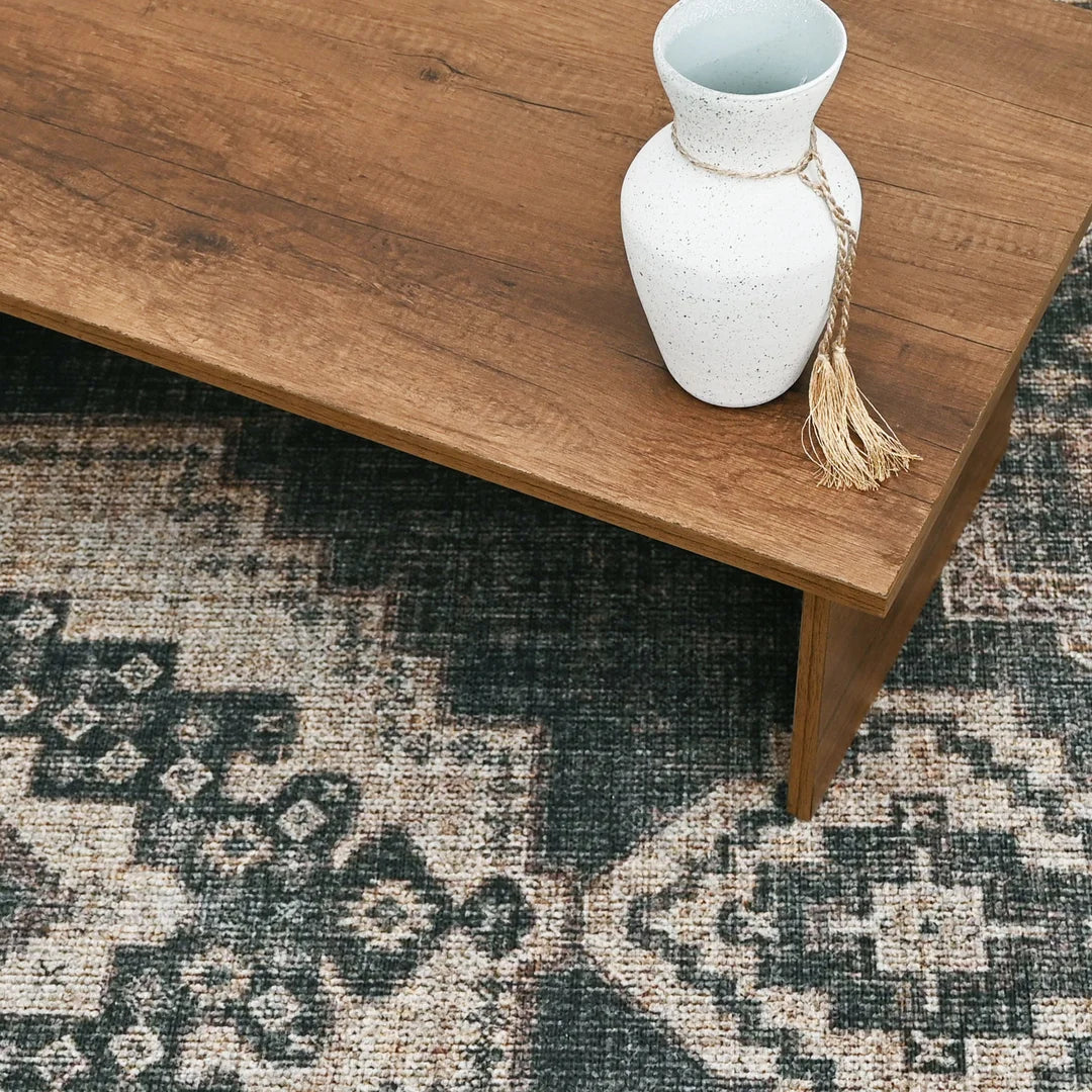 White vase with a tassel on a wooden table over a patterned rug