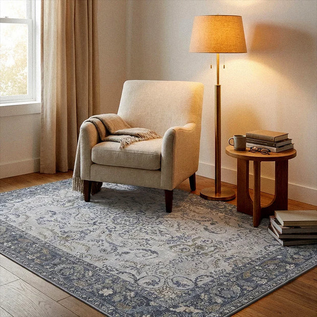 Cozy living room with beige armchair, lamp, and side table on a patterned rug.
