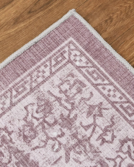 Close-up of a pink and white patterned rug on a wooden floor