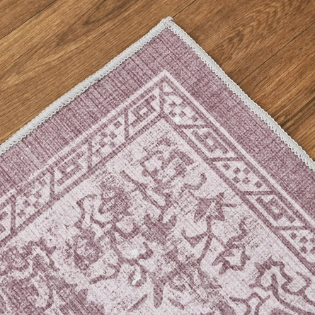Close-up of a pink and white patterned rug on a wooden floor