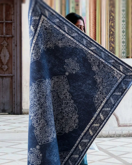 Person holding a large blue and white patterned rug indoors.