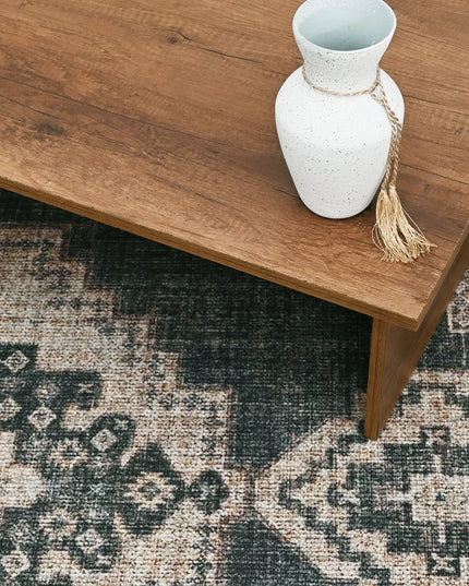 White vase with a tassel on a wooden table over a patterned rug